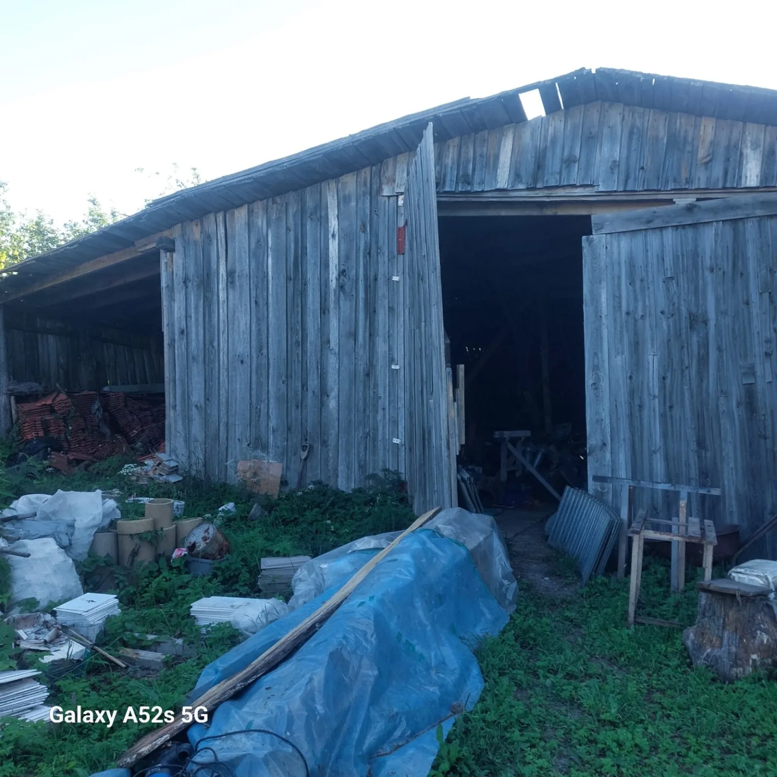 Old Latvian barn exterior with open doorway and reclaimed boards, good hero background.
